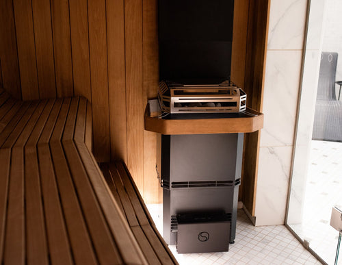 Saunum air L safety rail and heater beside wooden benches, wide room view.