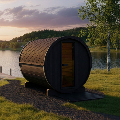 SaunaLife E8B black barrel sauna beside a lake at sunset.