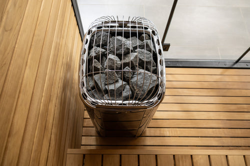 High-angle view of the Harvia Club heater's stone compartment and surrounding sauna benches.