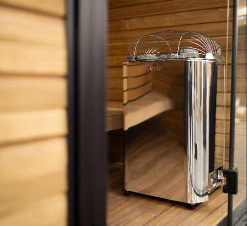 Harvia Club polished stainless-steel sauna heater viewed through an open glass door.