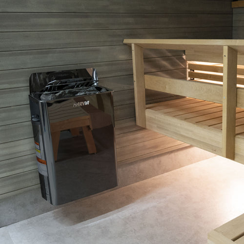 Harvia The Wall black heater mounted beside a wooden sauna bench.