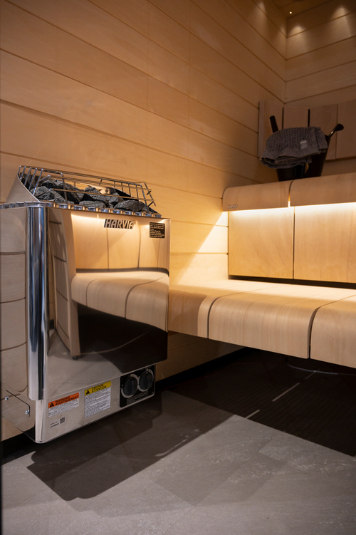 Low-angle view of a Harvia KIP stainless-steel heater beneath a sauna bench.