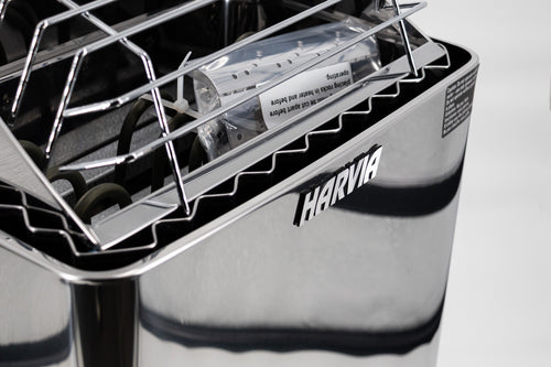 Close-up of the Harvia logo and polished casing below a KIP heater's top guard.