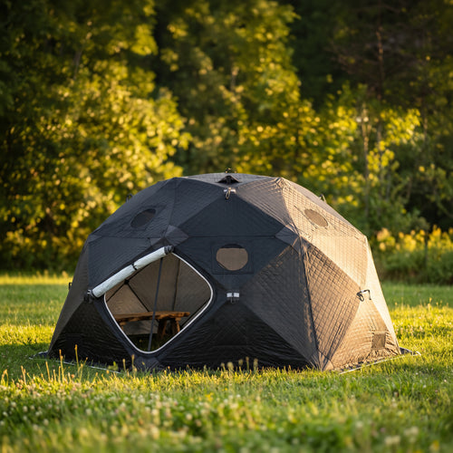 SaunaLife SaunaTrekker XL black dome-shaped tent in a wooded clearing.