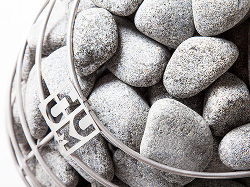 HUUM 2–4 inch rounded sauna stones in a DROP heater, close-up.