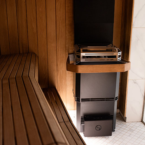 Saunum black Air L heater installed beside benches with wooden safety rail.