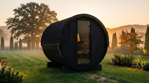 SaunaLife E8B black barrel sauna in a garden at sunrise.