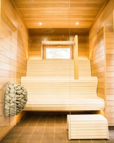 HUUM DROP heater beside pale wooden benches in a bright sauna.
