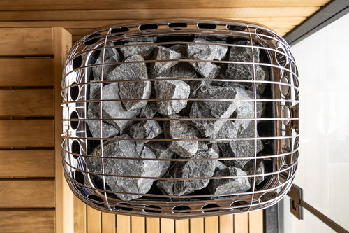 Overhead close-up of sauna stones beneath the Harvia Club heater's wire guard.