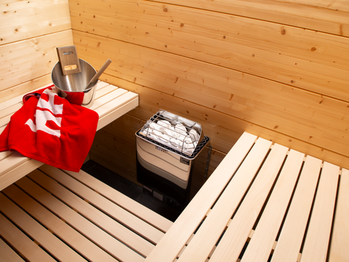 Harvia KIP heater installed between wooden sauna benches, viewed from above.