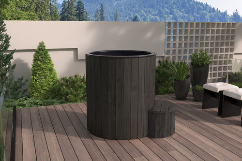 SaunaLife S1B black immersion tub beside a garden wall.