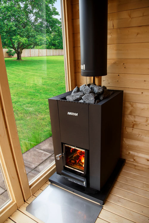 Harvia Linear 18 Compact stove installed beside a glass sauna door and wooden wall.