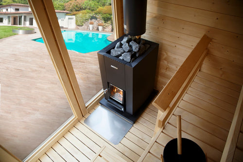 High-angle view of a Harvia Linear 18 Compact stove beside a glass sauna door.