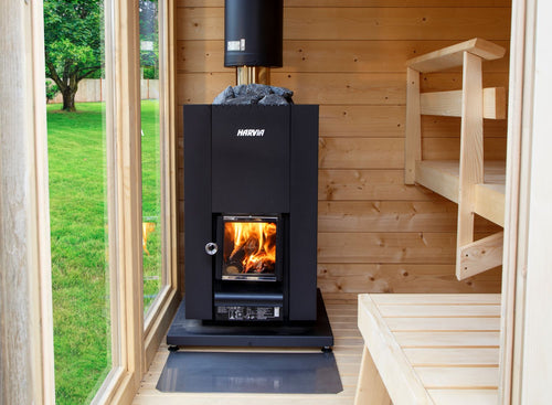 Front view of a Harvia Linear 18 Compact stove between a glass door and sauna benches.